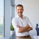 Portrait of smiling mid adult businessman standing at corporate office